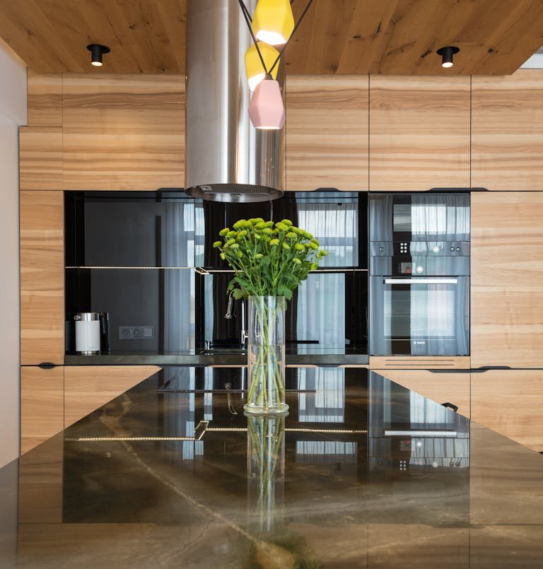 Contemporary kitchen interior with built in appliances and dining counter under creative chandelier